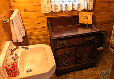 looking into the bathroom from the hallway of Cedar Cliff Cottage - sink, towel rack with towels, cabinet, window