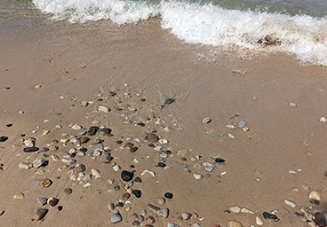 waves lapping at the Lake Huron shoreline with lake stones dotting the beach at Cedar Cliff Cottage