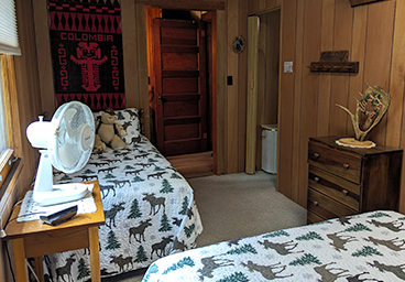 looking out into the hallway from bedroom 2 of Cedar Cliff Cottage - double bed, twin bed, desser, window, tabletop fan